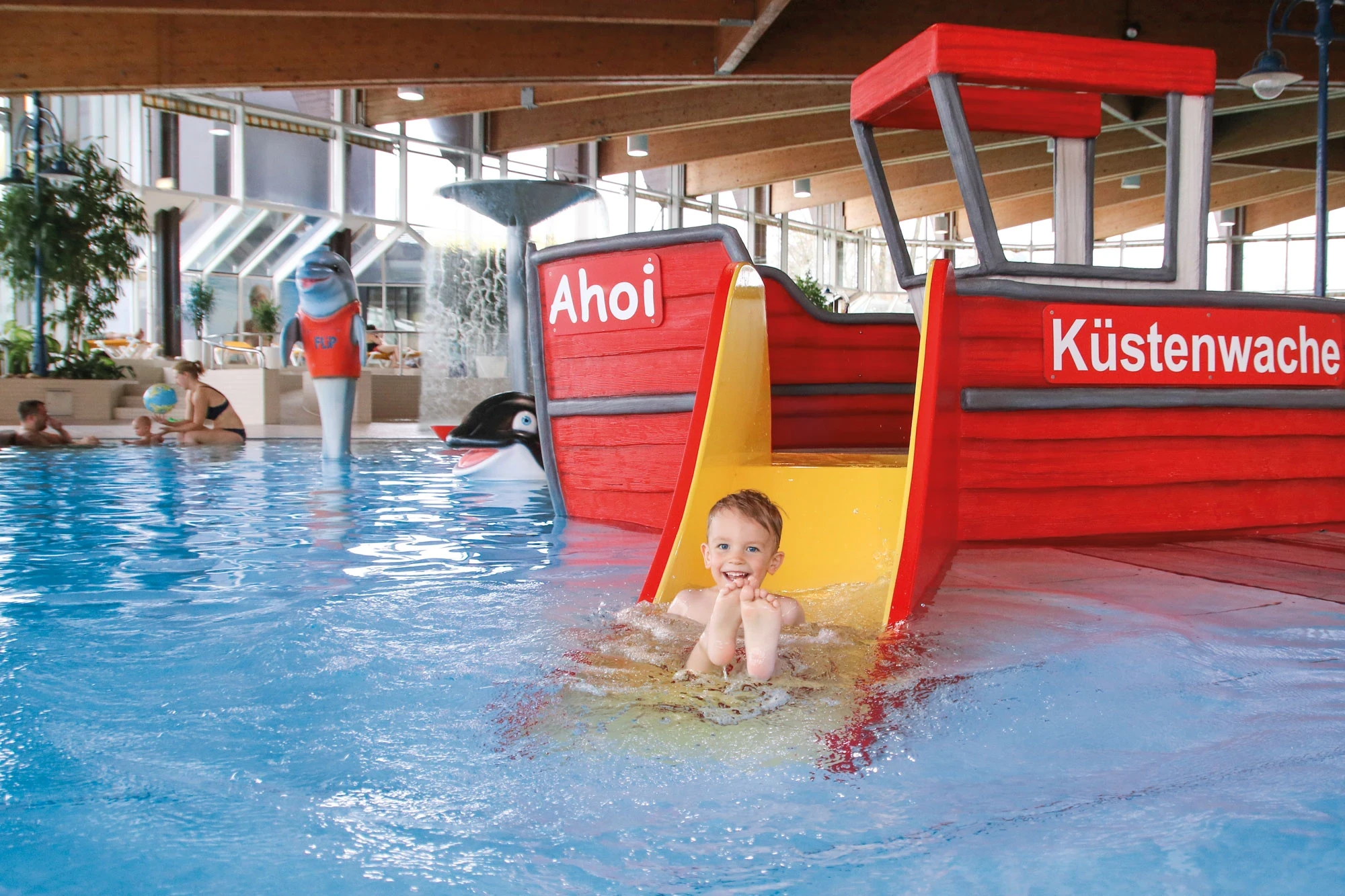 Kleiner Junge erfreut sich im Nichtschwimmerberich am Boot der Küstenwache.
