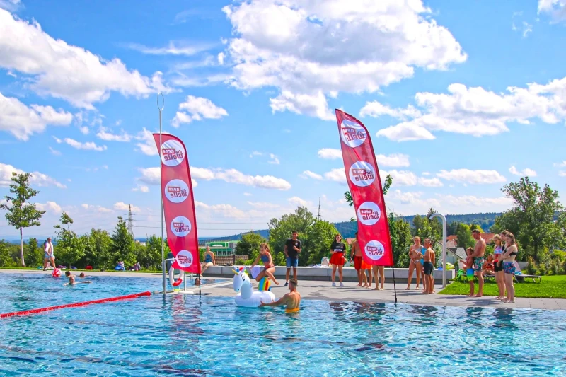 Kind h&uuml;pft auf Einhorn-Wasserspielzeug w&auml;hrend Freibad-Event