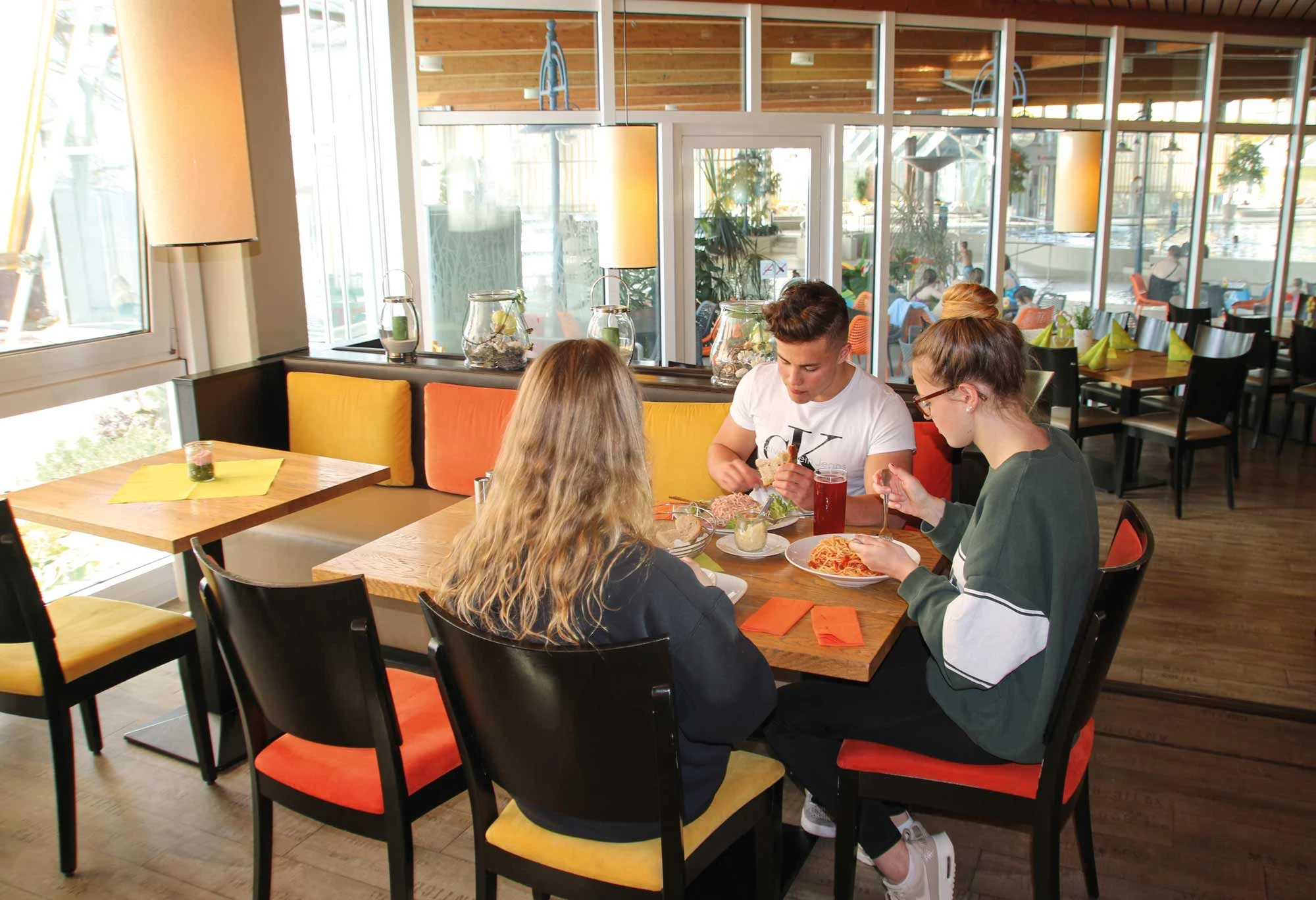 Gruppe junger Menschen beim gemütlichen Mittagessen im Panorama-Bad Restaurant