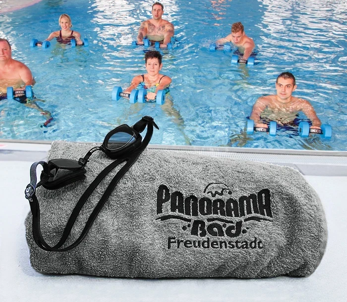Handtuch mit Schwimmbrille auf dem Beckenrand – im Hintergrund ein Aqua-Fitness Kurs